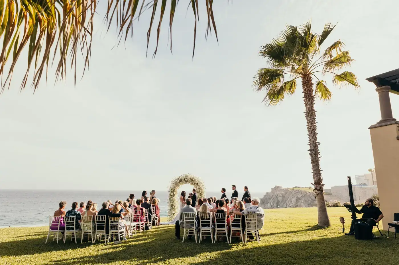 Outdoor wedding ceremony with palm trees and an ocean view in Los Cabos