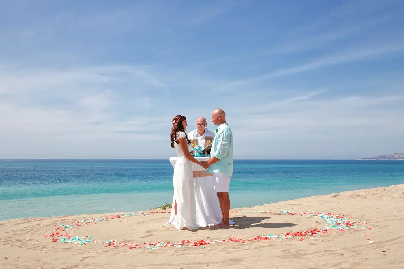 Beach wedding ceremony with a circle of petals on the sand in Los Cabos