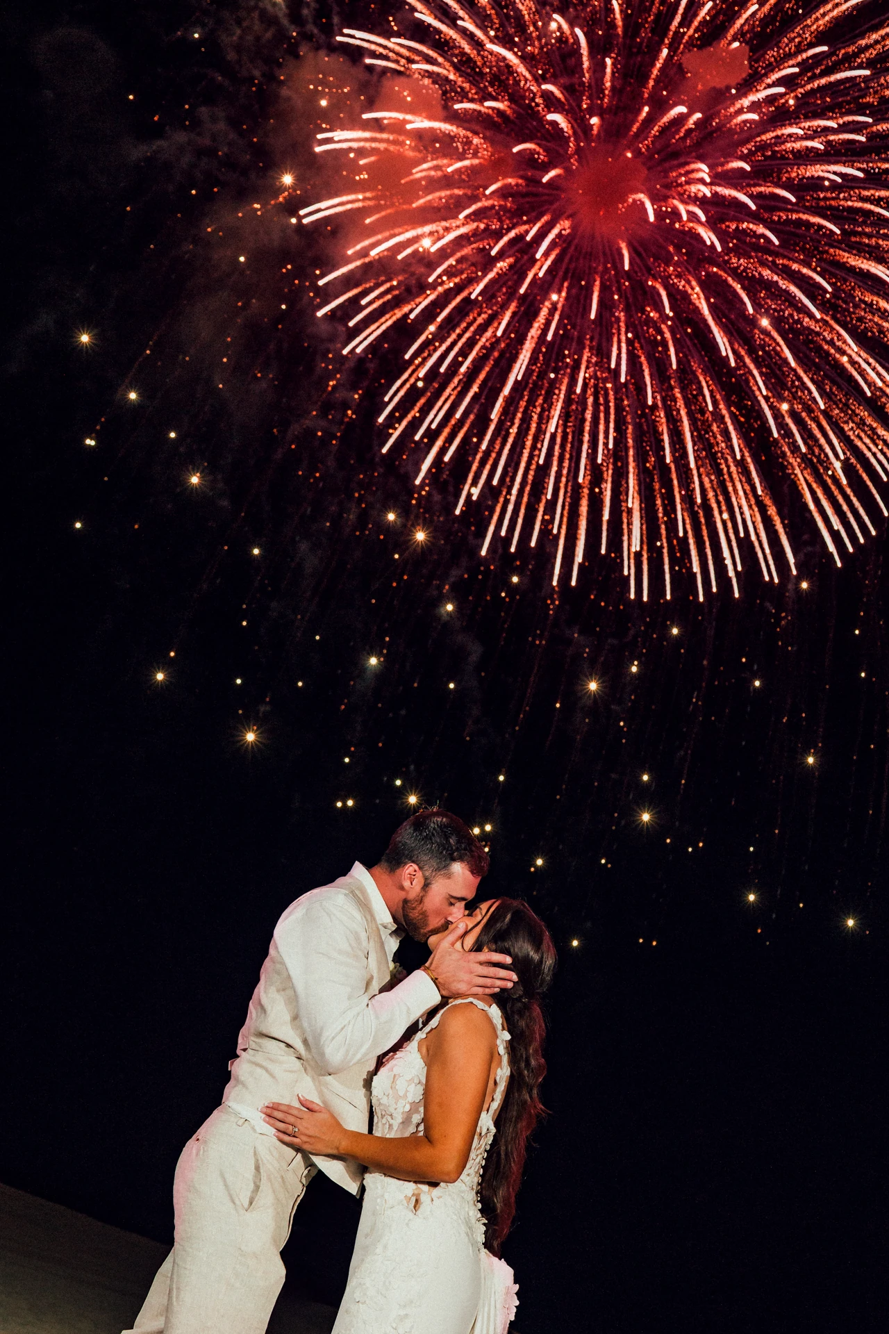 Bride and groom kissing under fireworks at their Los Cabos wedding