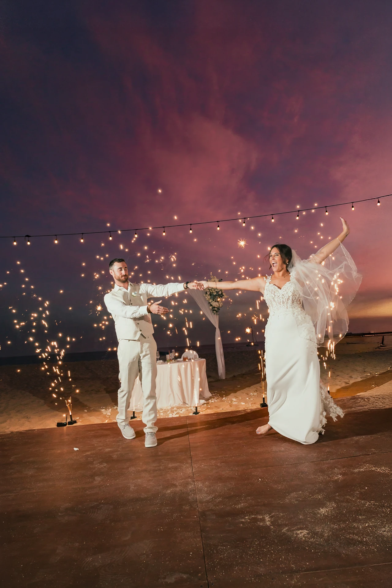 Couple with a sparkler send-off under string lights at dusk in Cabo San Lucas