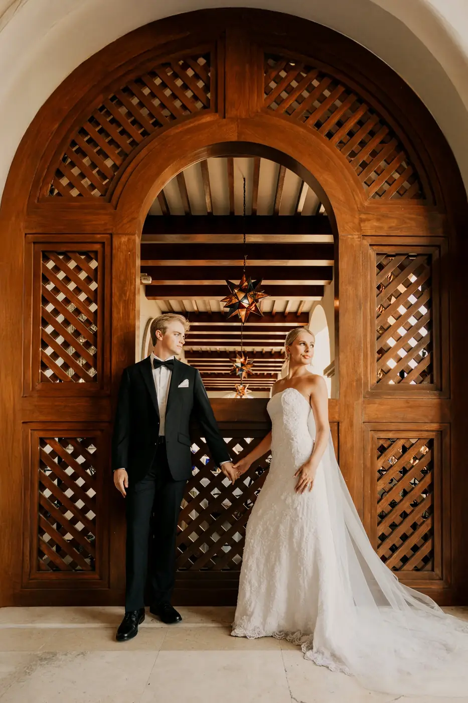 Bride and groom at an ornate carved door, luxury Cabo San Lucas wedding