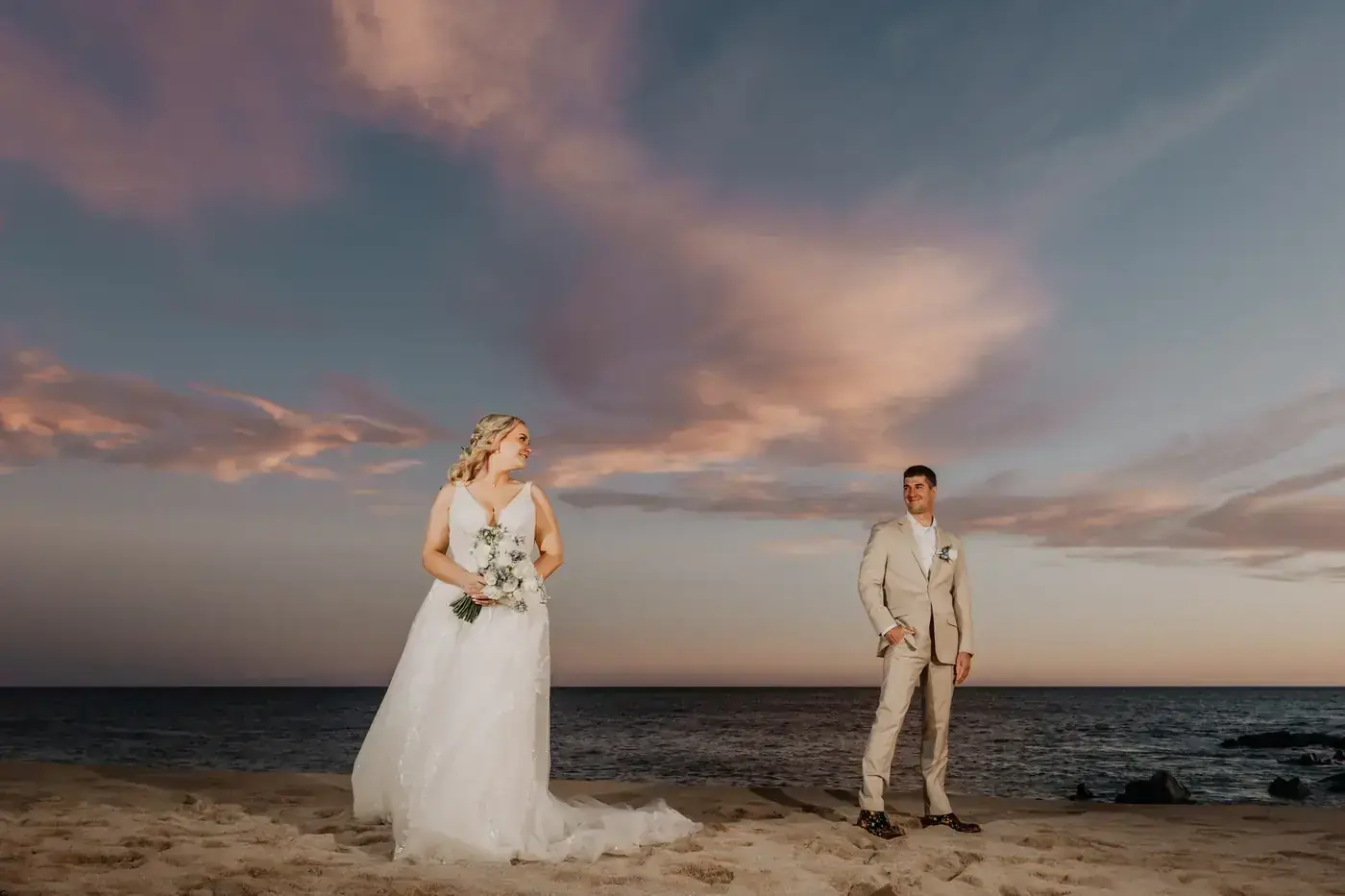 Couple on a Cabo beach at dusk with pink clouds over the Pacific