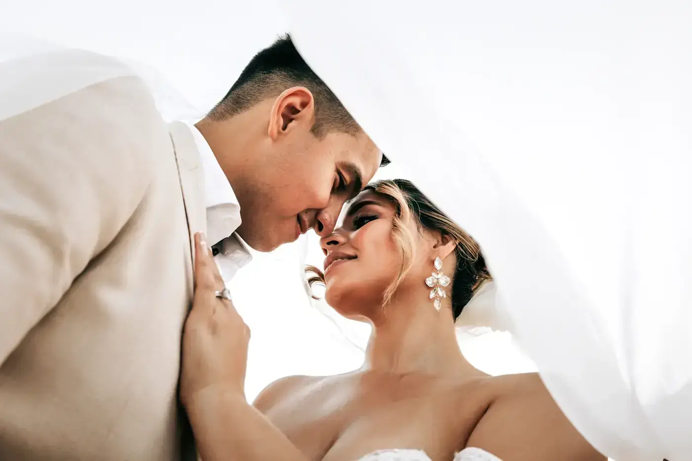 Bride and groom kissing under her veil right after their vows in Cabo