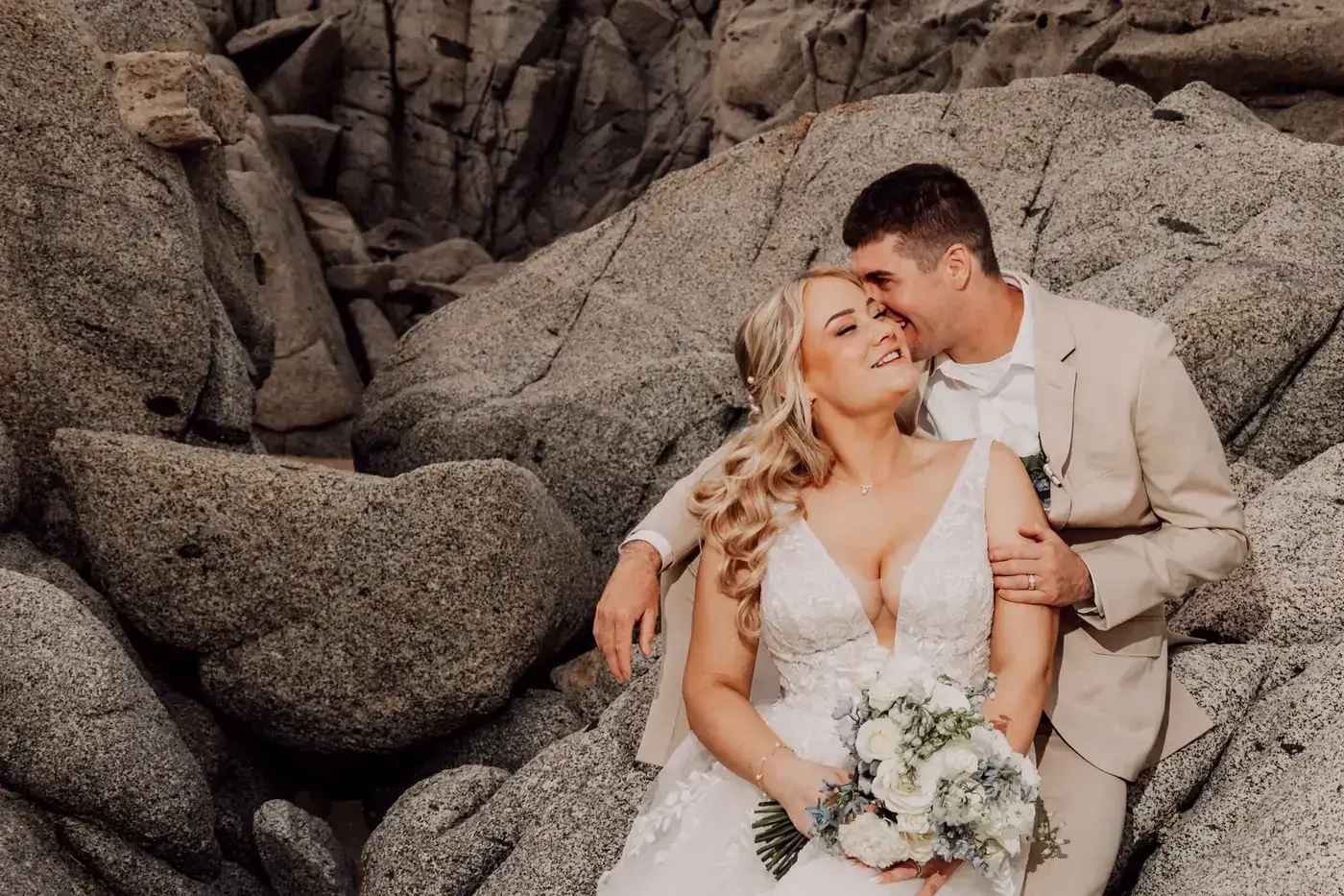 Couple laughing on the granite rocks by the sea in Los Cabos