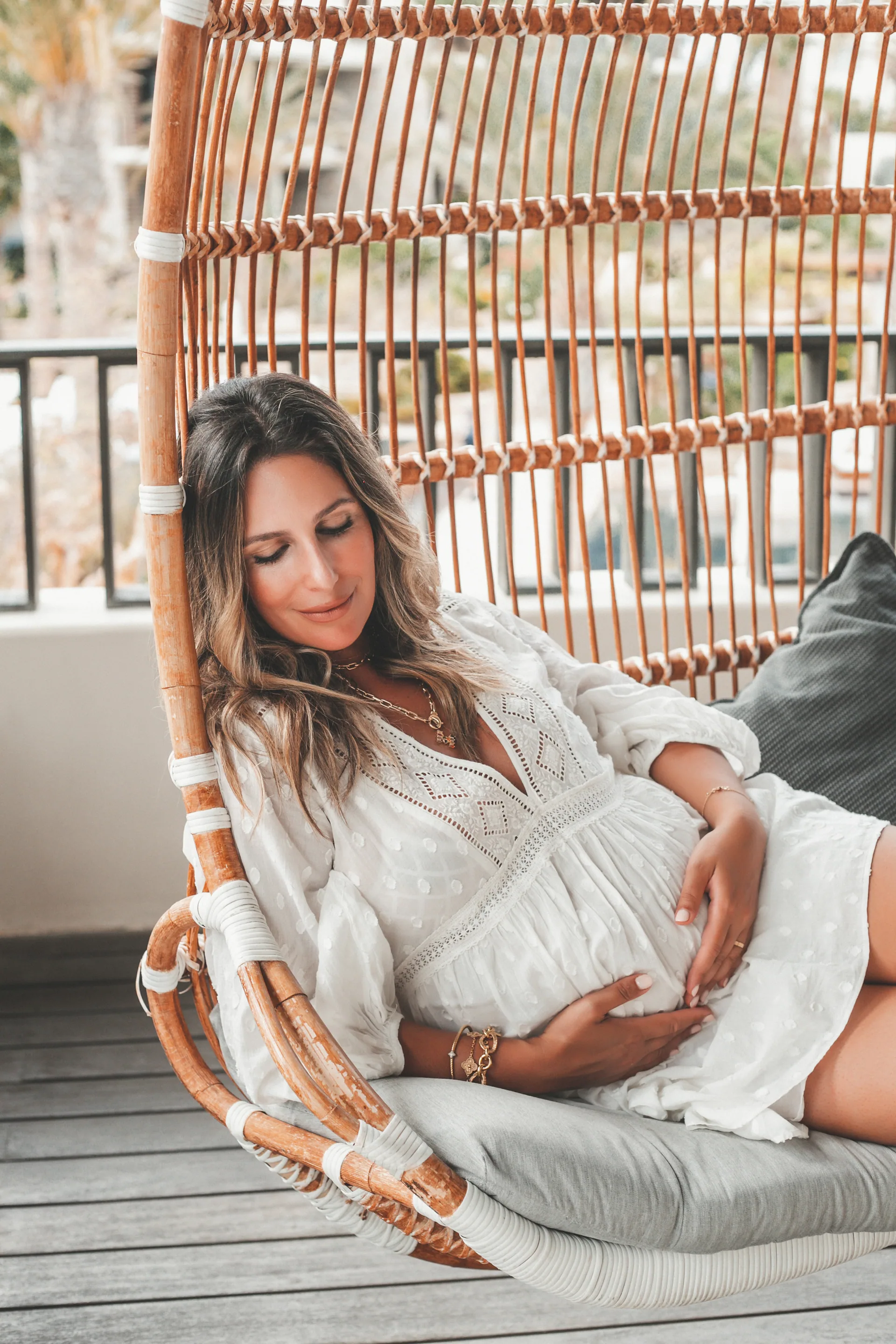 Expecting mother in a white dress on a swing at Chileno Bay, Los Cabos
