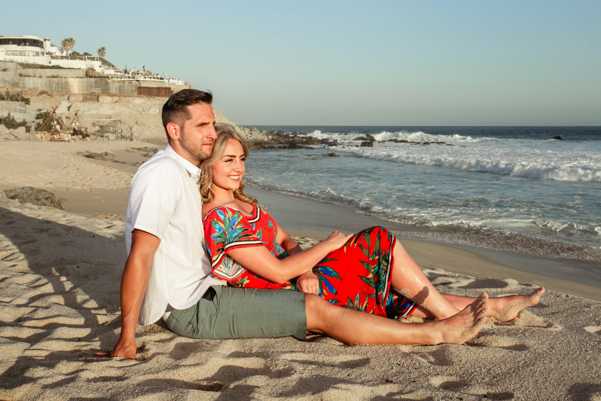 Couple sitting together on the sand at sunset during their couples photo session in Cabo San Lucas