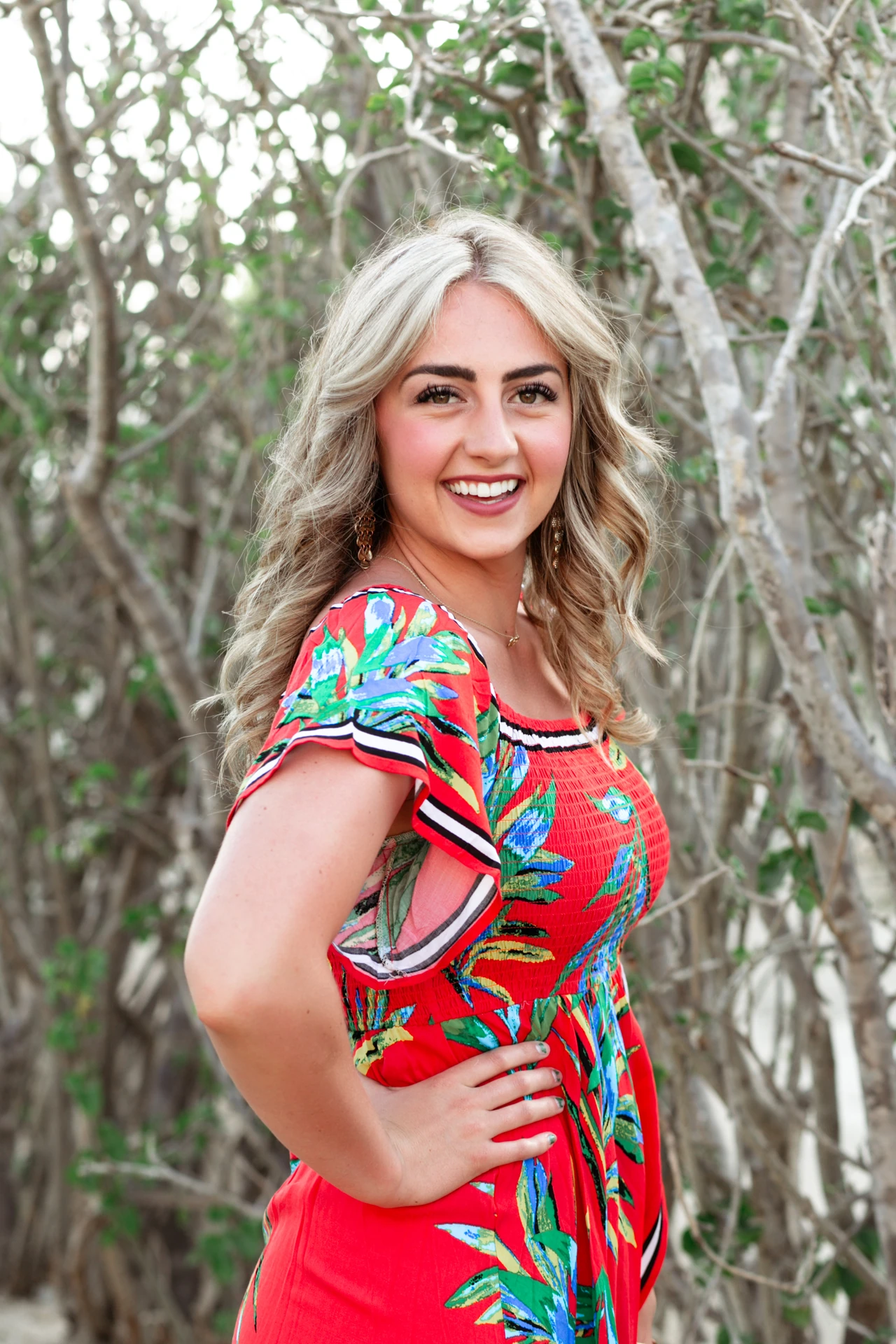 Portrait of a woman in a red floral dress during a couples photo session at Playa Monumentos, Cabo San Lucas