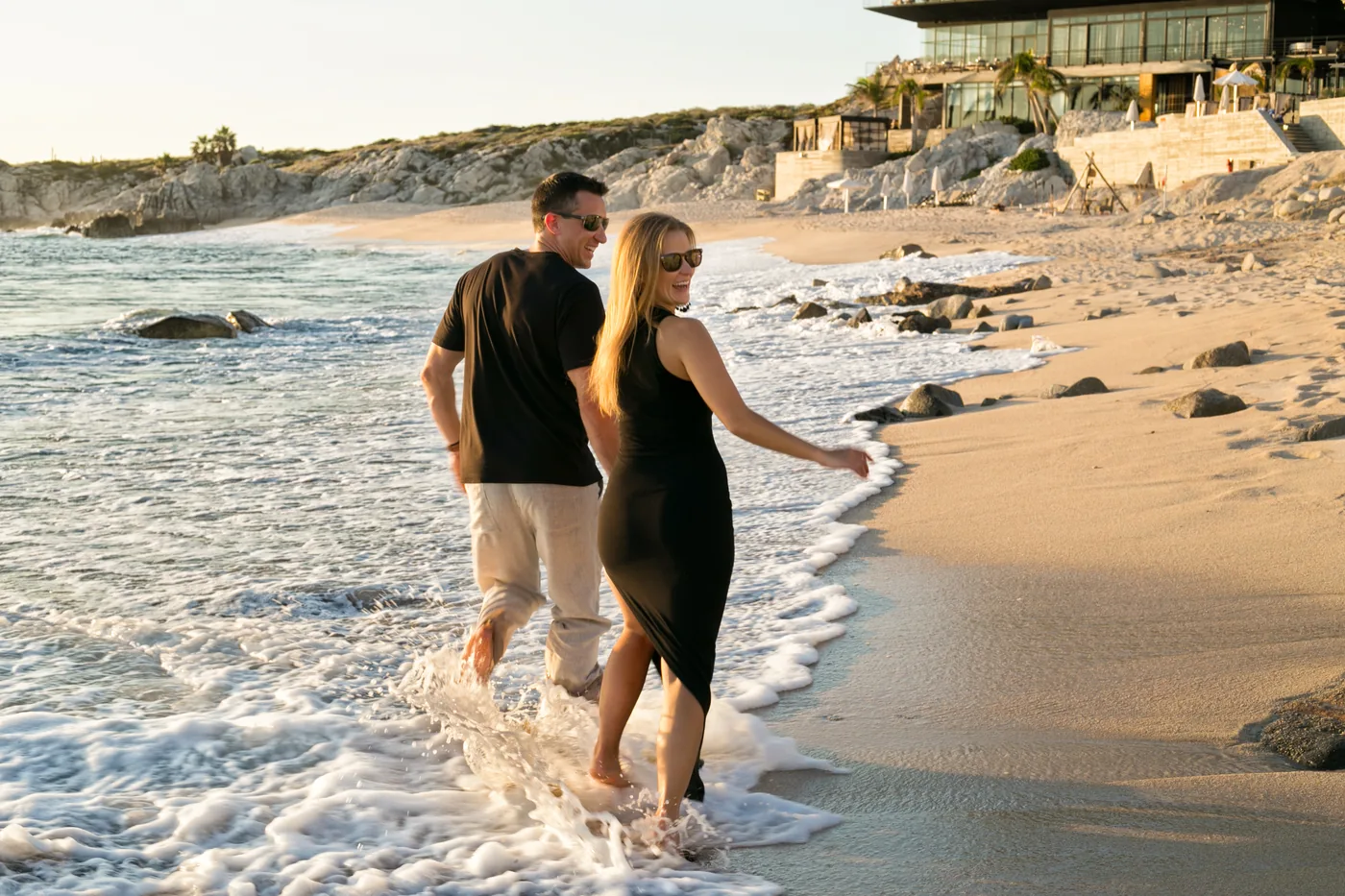 Couple walking hand in hand on the beach at The Cape Thompson Hotel